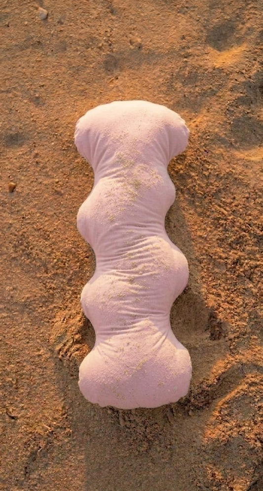 Pinkish-white Pillow on sandy surface