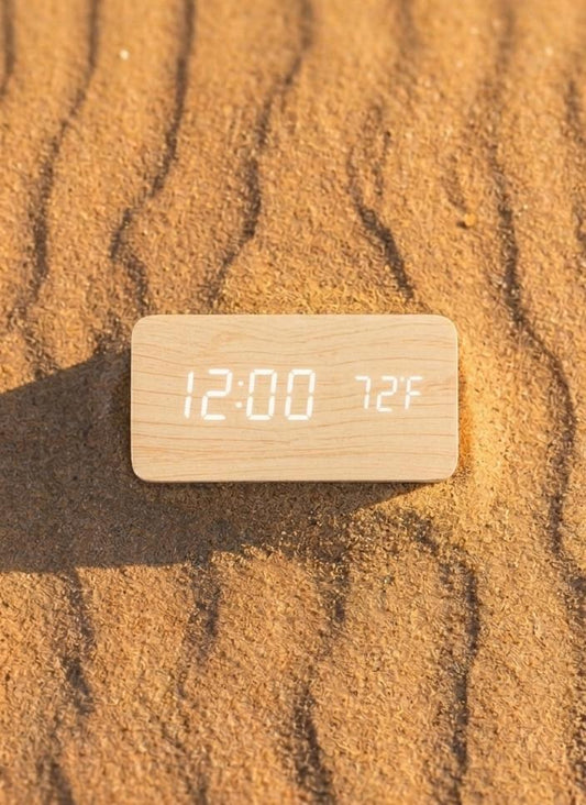 Wooden digital clock displaying time and temperature on sand