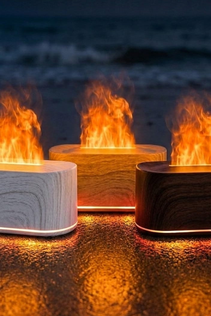 Three fire pits with flames on a beach at night