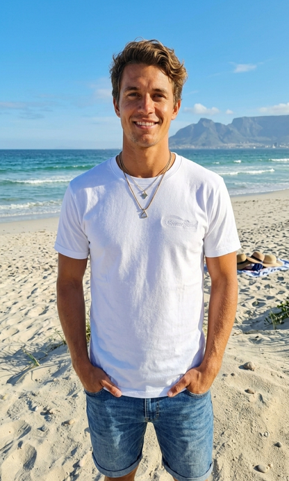 Man standing on a beach with ocean and mountain in the background