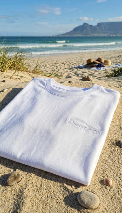White t-shirt with a brand logo on a sandy beach with Table Mountain in the background