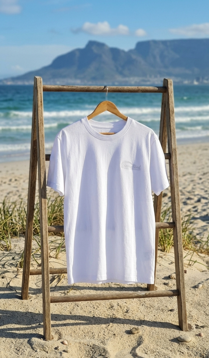 White t-shirt on a wooden stand with a mountain and beach in the background