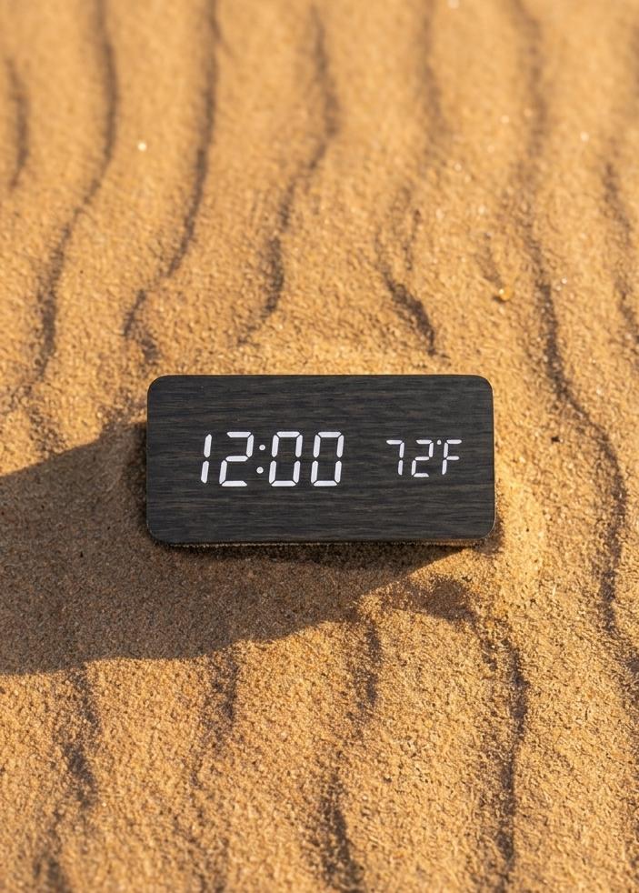 Digital clock displaying time and temperature on sand